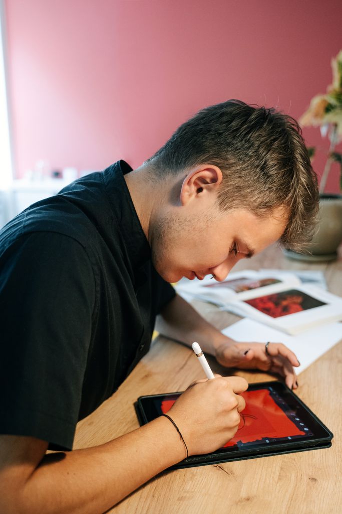 Focused young graphic designer drawing on a tablet in a modern workspace.